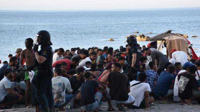 Cientos de personas migrantes reciben atención sanitaria de profesionales del INGESA y voluntarios de Cruz Roja, en la playa del Trampolín de Ceuta.