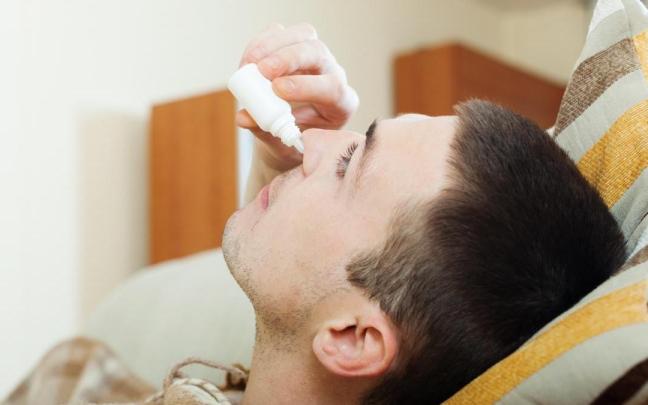 Un hombre se aplica gotas nasales.