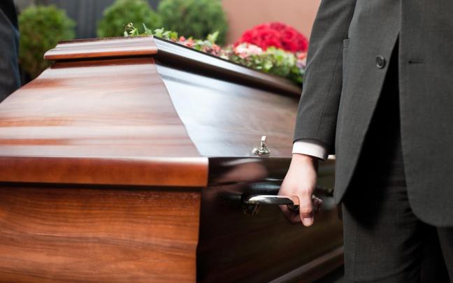 Una persona porta un ataúd.