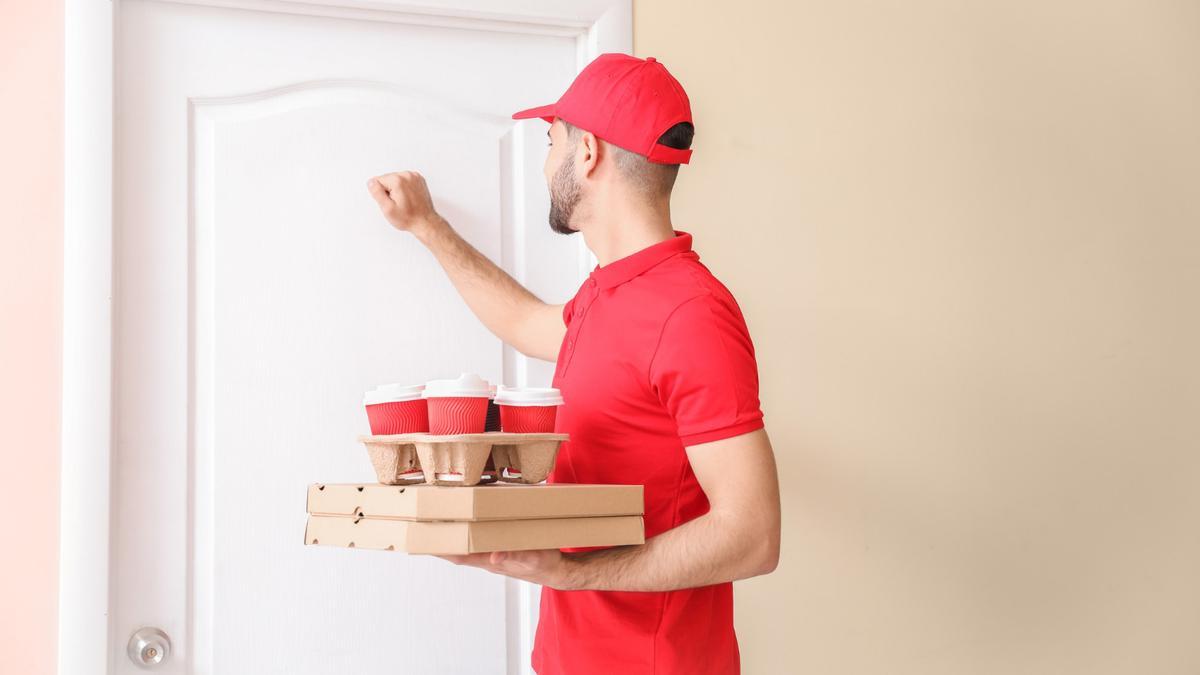Un repartidor lleva comida a una casa.