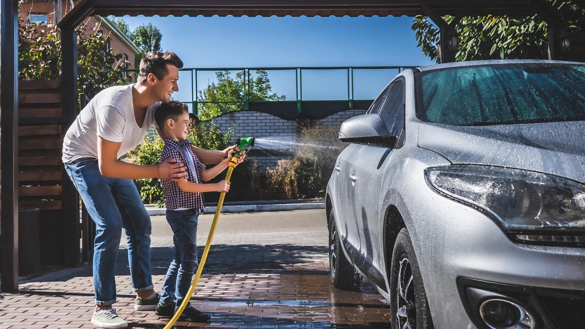 Padre e hijo lavando el coche con una manguera.