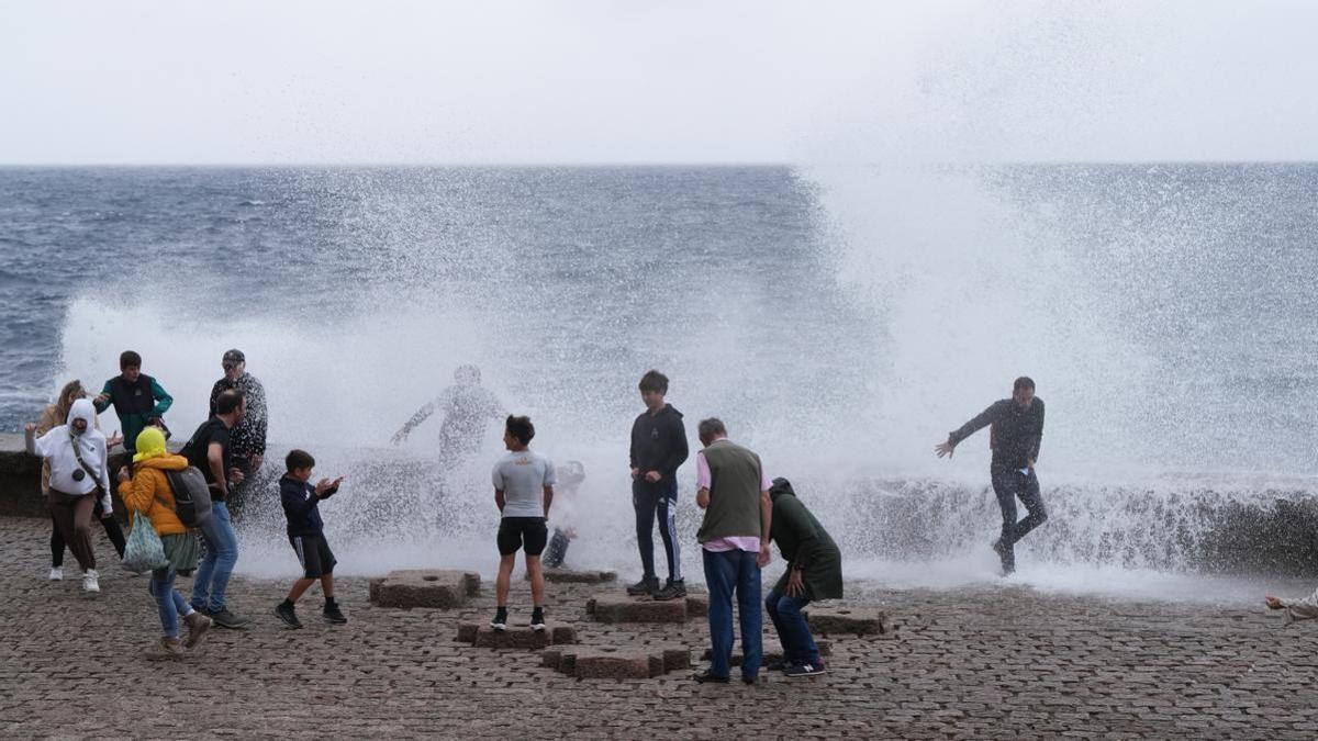 Varias personas se mojan con las olas en el Peine del Viento