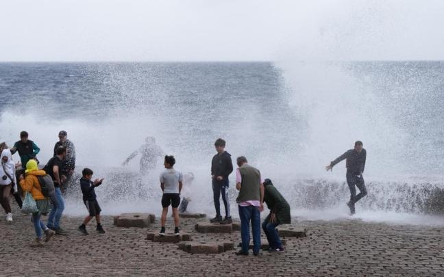 Varias personas se mojan con las olas en el Peine del Viento