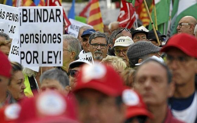 Decenas de personas portan carteles y banderas durante una concentración de pensionistas. | FOTO: E.P.
