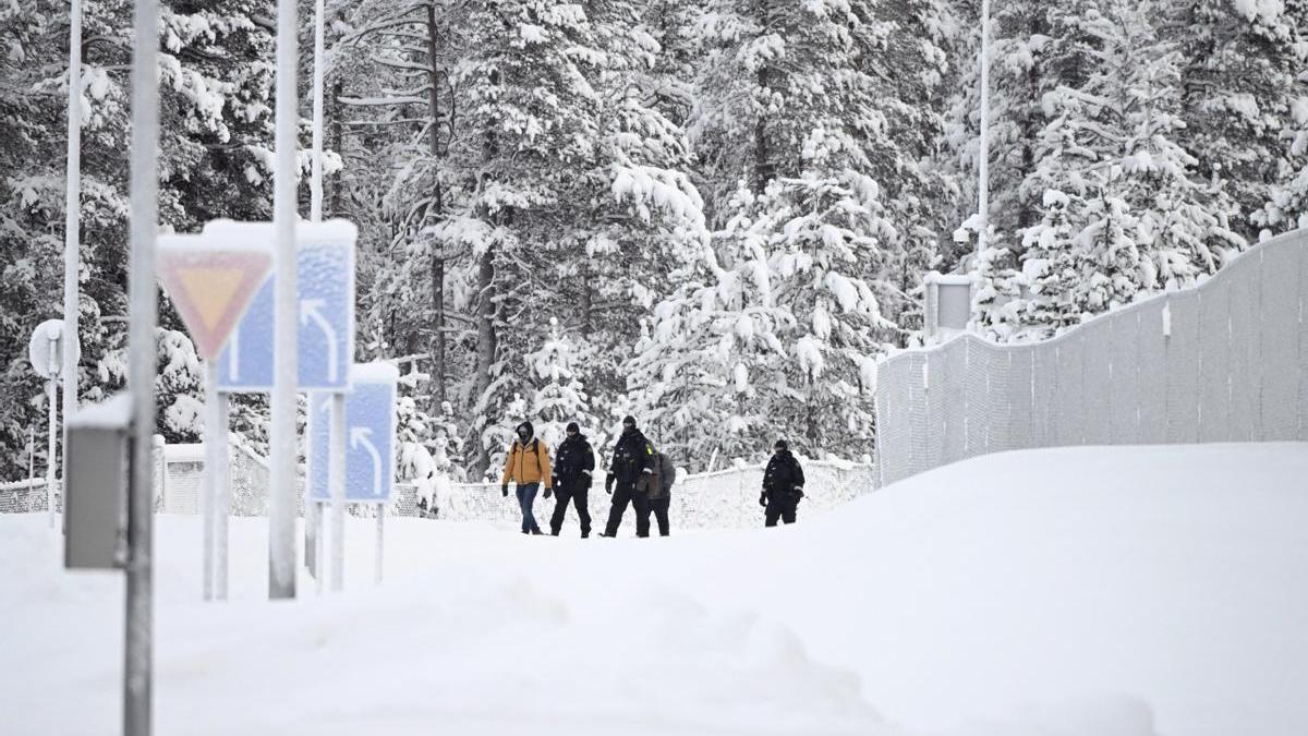 Guardias fronterizos finlandeses escoltan a dos migrantes en el puesto fronterizo de Raja-Jooseppi.