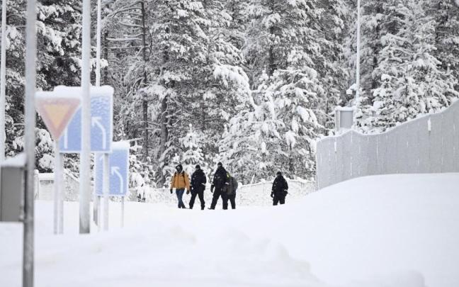 Guardias fronterizos finlandeses escoltan a dos migrantes en el puesto fronterizo de Raja-Jooseppi.