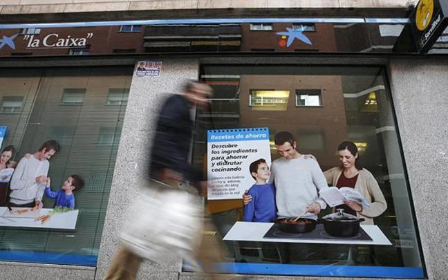 Un hombre pasa delante de una oficina de La Caixa en Madrid.