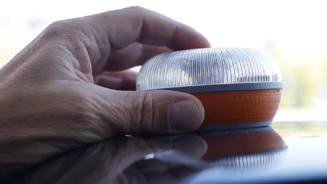 Una persona coloca una baliza V16 en el techo de un coche.