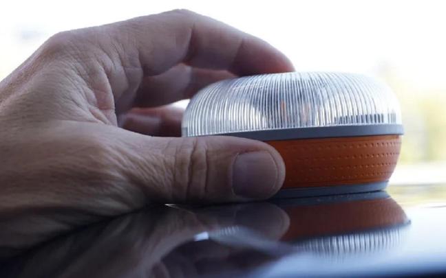 Una persona coloca una baliza V16 en el techo de un coche.