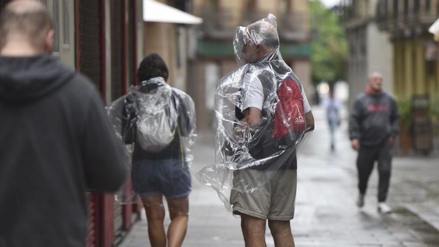 Dos personas se protegen de la lluvia con chubasqueros.