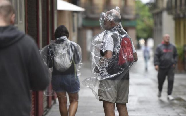 Dos personas se protegen de la lluvia con chubasqueros. / EP Dos personas se protegen de la lluvia con chubasqueros.