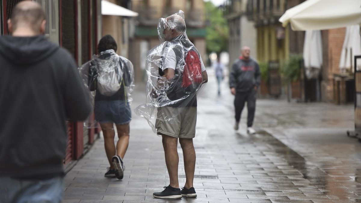 Dos personas se protegen de la lluvia con chubasqueros.