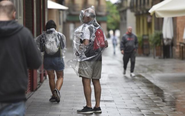 Dos personas se protegen de la lluvia con chubasqueros. / EP Dos personas se protegen de la lluvia con chubasqueros.