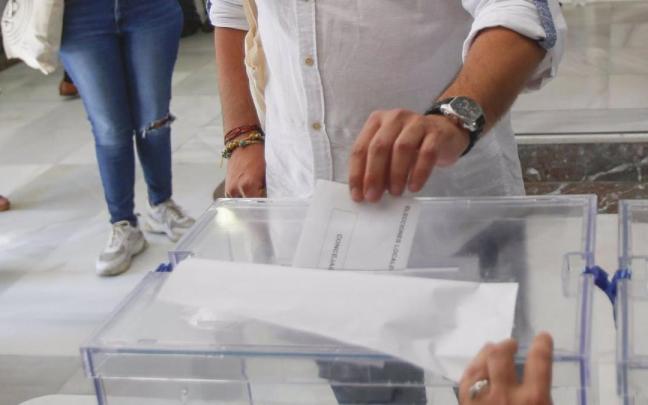 Una persona deposita su voto en la urna Una persona deposita su voto en la urna