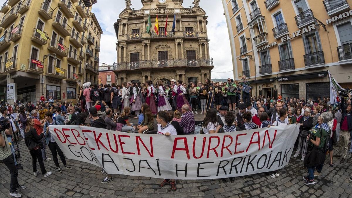 Protesta festiva en la plaza del Ayuntamiento tras una pancarta que reza 'Debekuen aurrean, gora jai herrikoiak' (frente a las prohibiciones, viva las fiestas populares).
