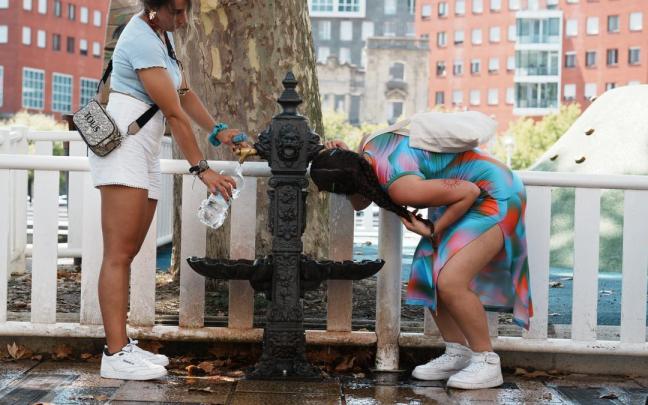 Dos mujeres beben agua de una fuente instalada en la calle en Bilbao