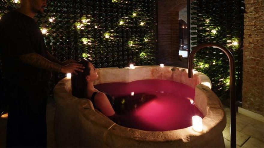 Una mujer toma un baño en vino en un spa.