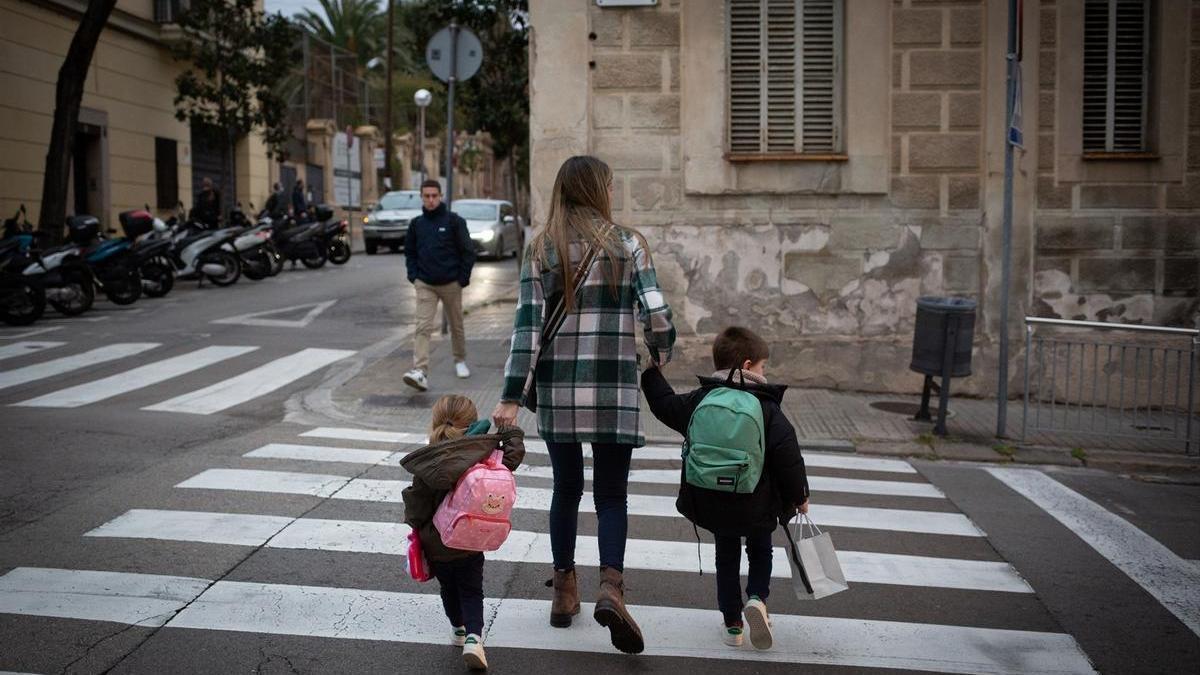 Dos niñas de la mano con su madre.