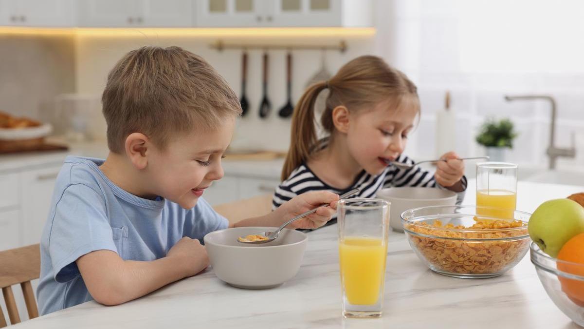 Niños desayunan cereales.