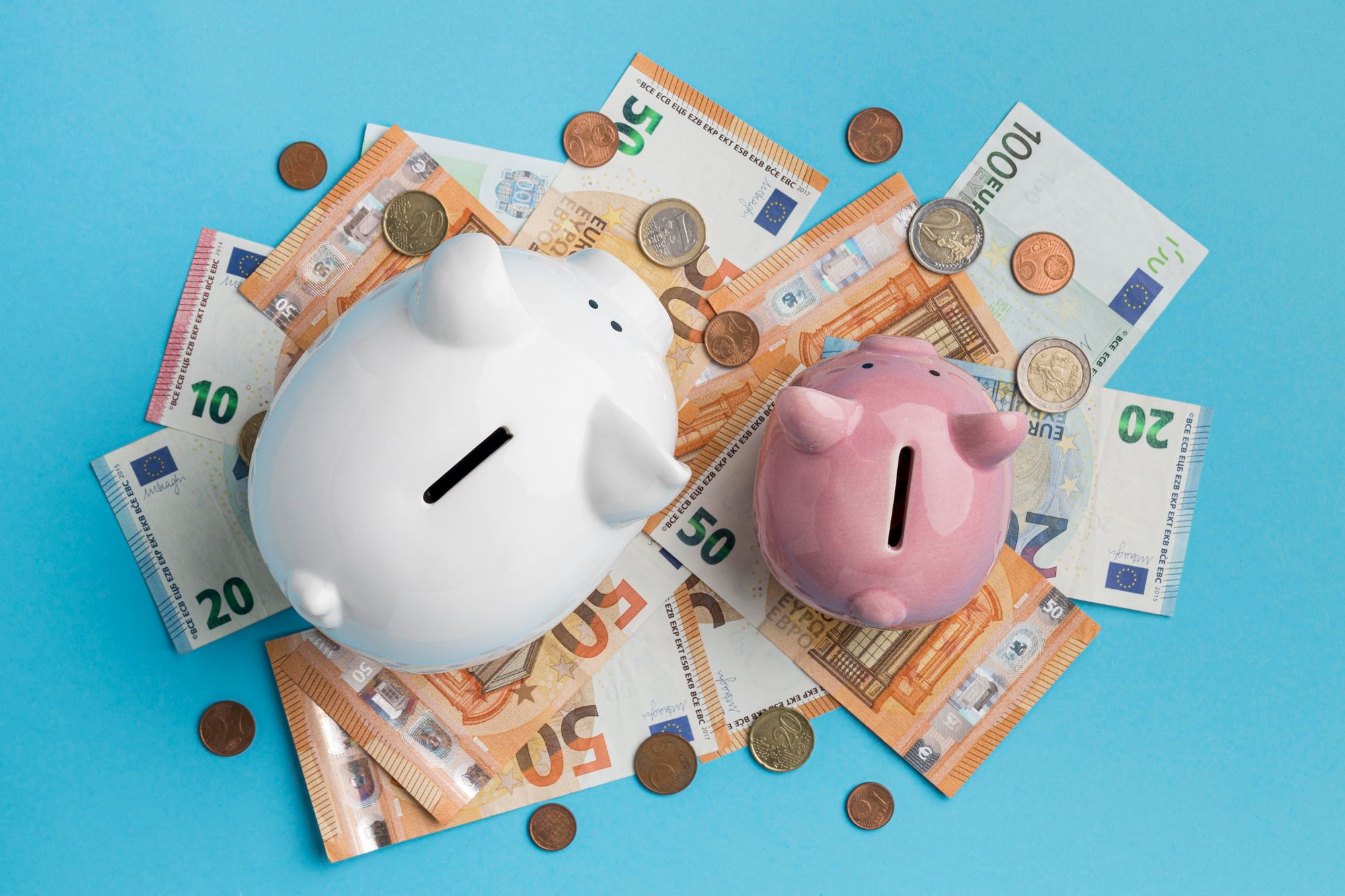 Dos huchas de cerdito sobre billetes de euro.