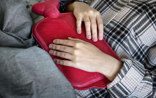 Una mujer con una bolsa de agua caliente sobre el vientre.