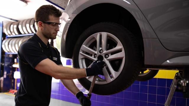 Un operario arreglando el neumático de un coche eléctrico