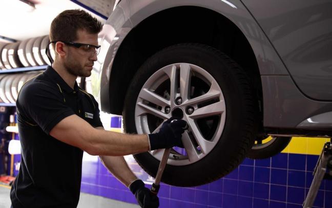 Un operario arreglando el neumático de un coche eléctrico