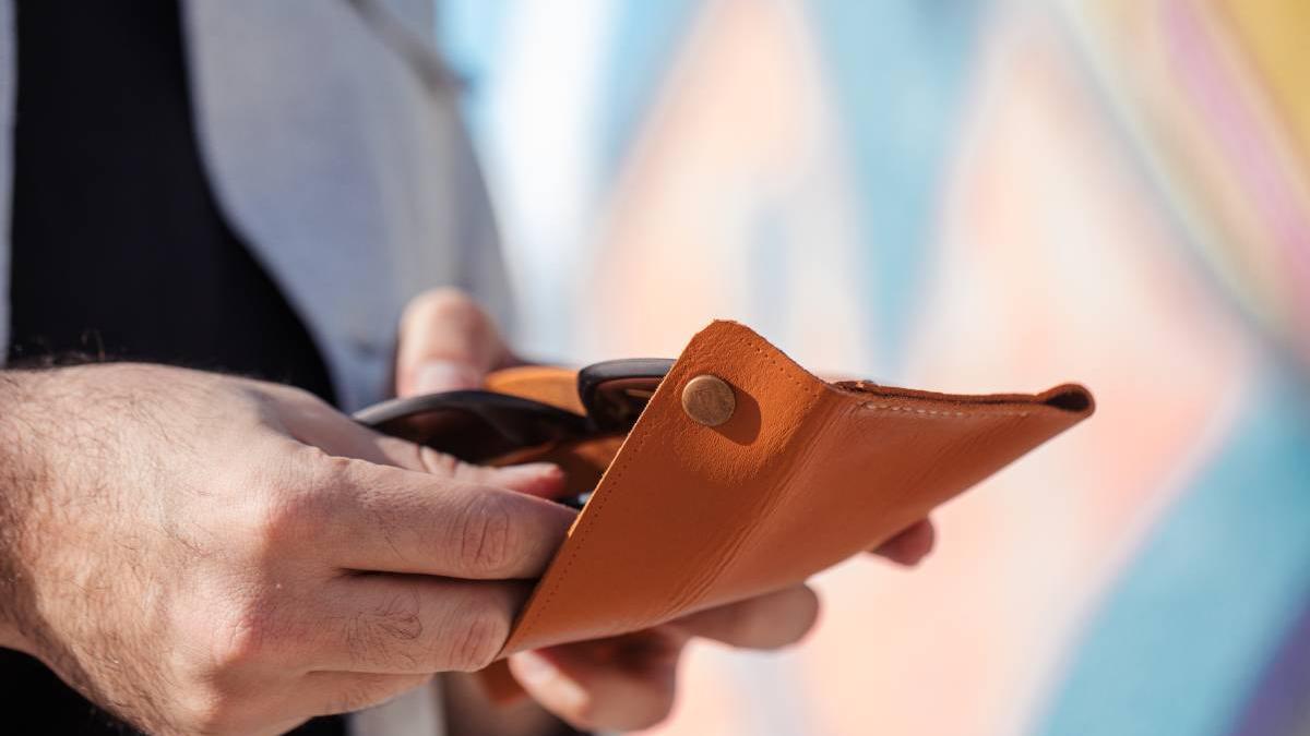 Una persona guarda su dinero en la cartera