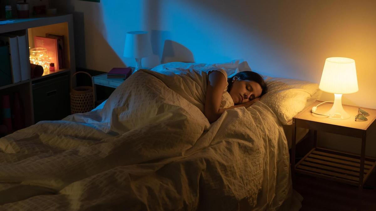 Una mujer duerme con dos lámparas encendidas.