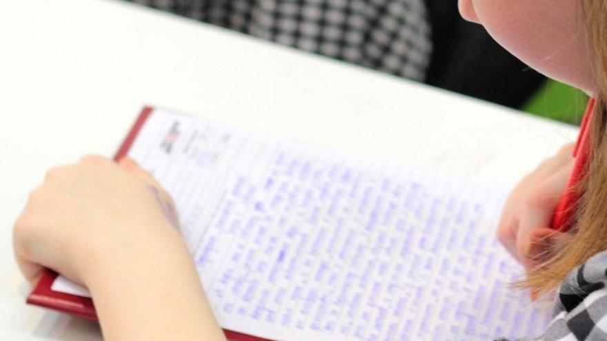 Alumna escribiendo en un centro escolar.