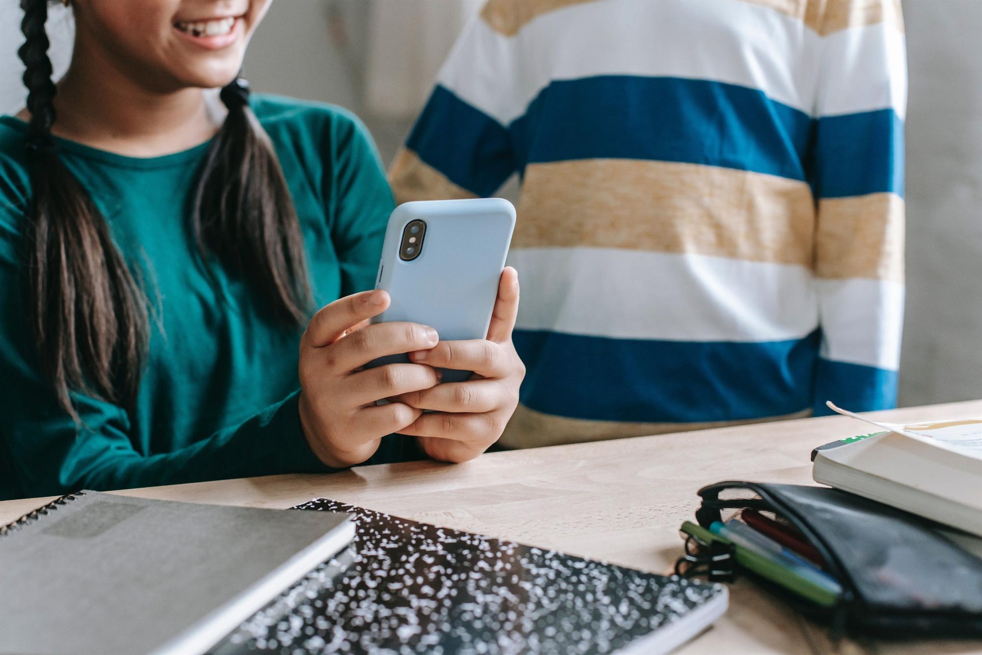 Unos niños se divierten utilizando un teléfono móvil.