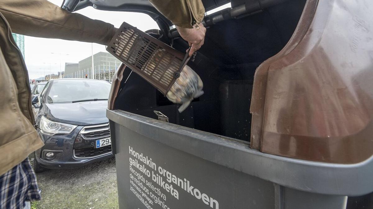 Un ciudadano arroja sus residuos orgánicos a un contenedor específico.