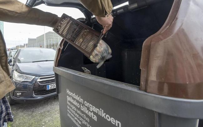 Un ciudadano arroja sus residuos orgánicos a un contenedor específico.