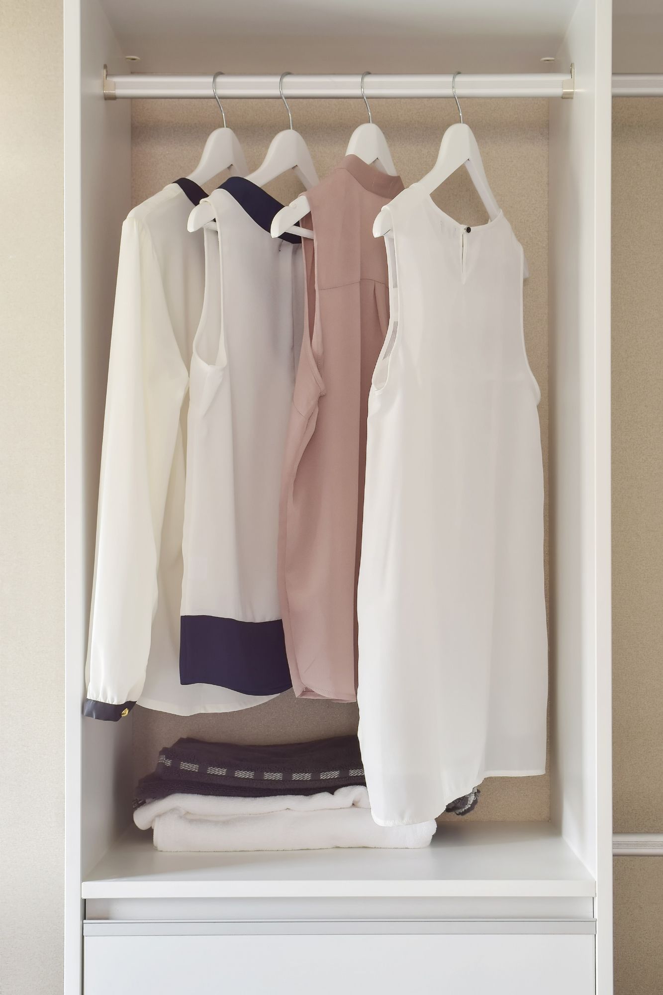 Varias camisas de mujer blancas colgadas en un armario.
