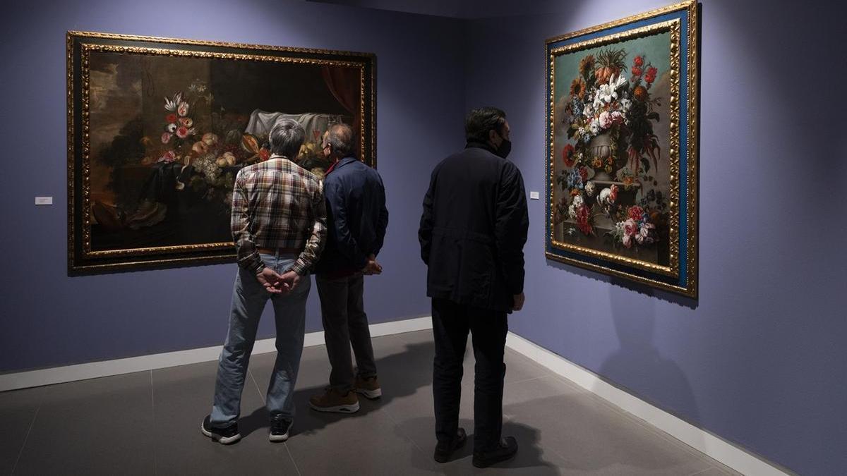 Varias personas observan dos obras de Van Dyck en una exposición en Sevilla.