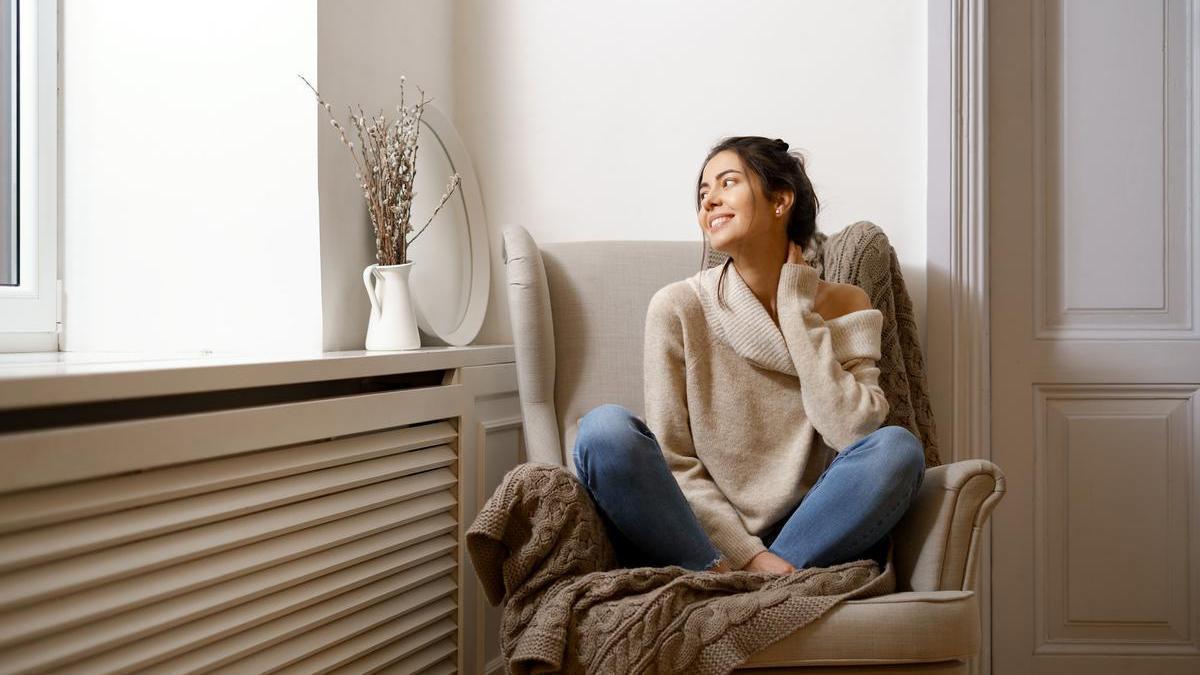 Chica joven en casa sentada en un sillón al lado de la ventana