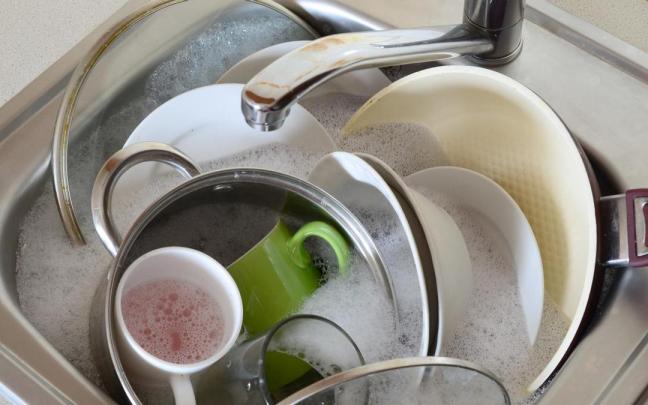 Un fregadero lleno de utensilios de cocina para fregar. Un fregadero lleno de utensilios de cocina para fregar.