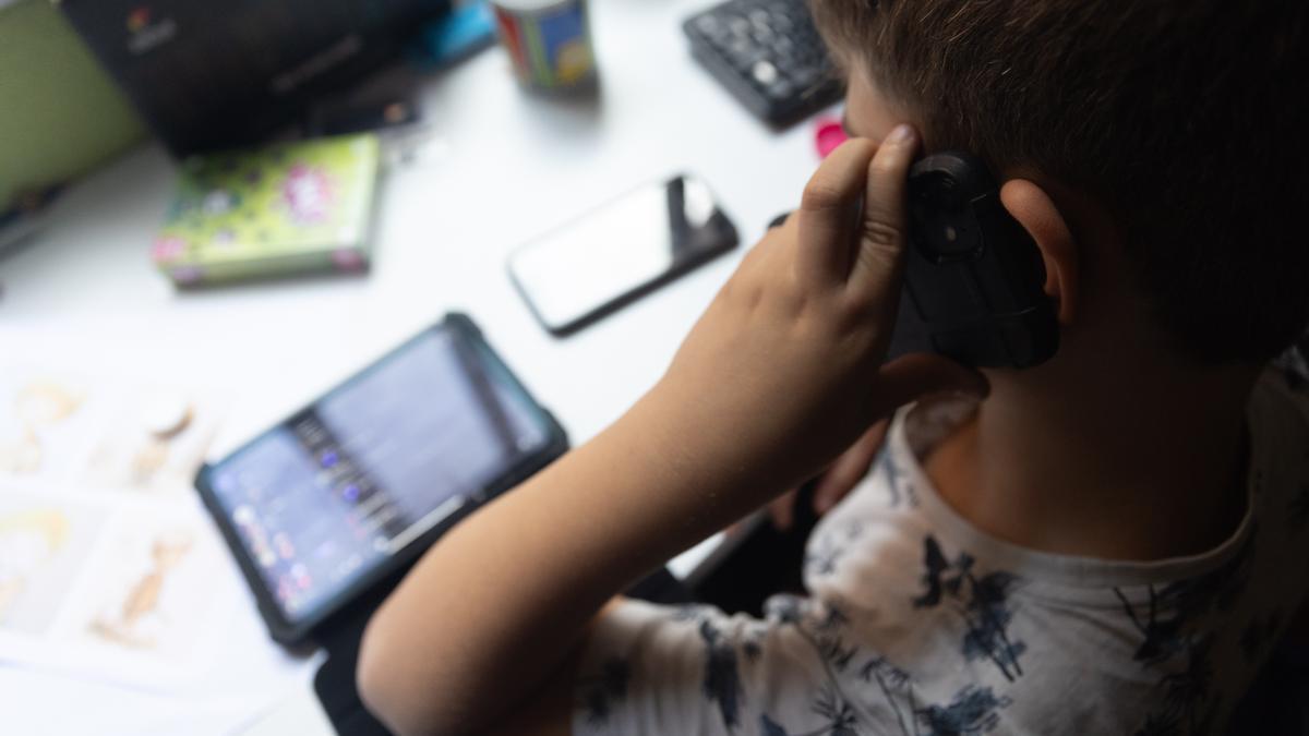 Un niño usa el teléfono móvil y una tablet.