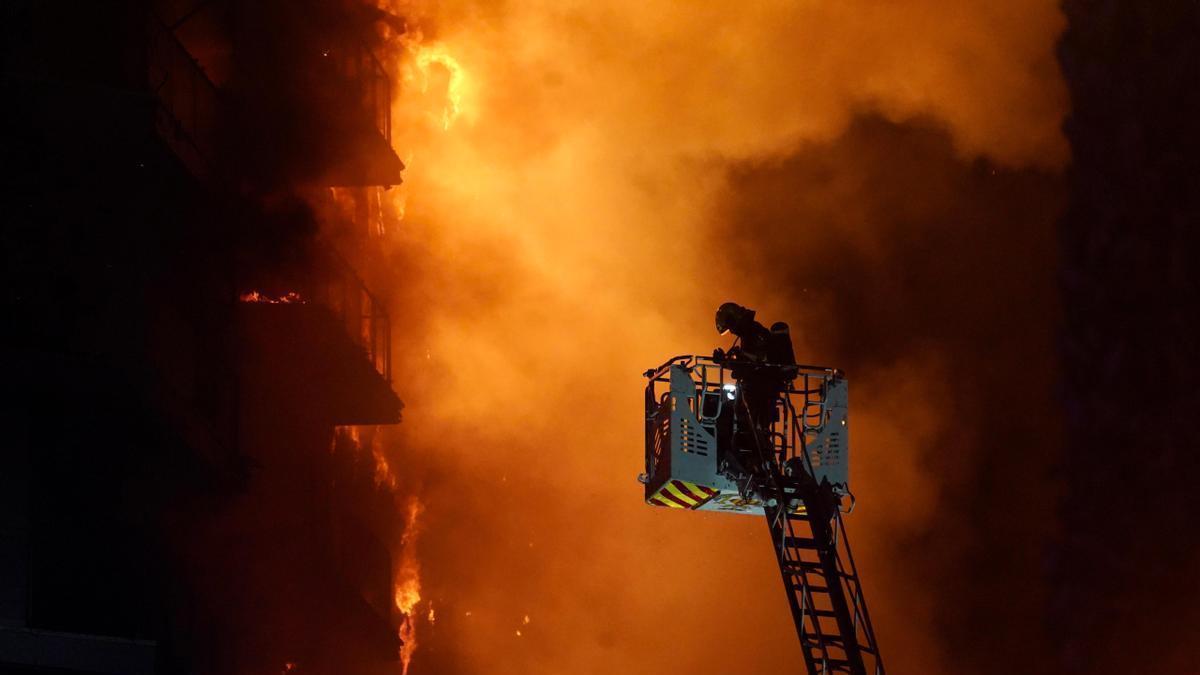 Un bombero trata de apagar el edificio en llamas.