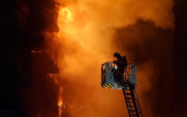 Un bombero trata de apagar el edificio en llamas.