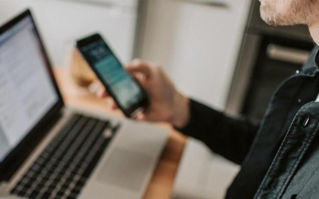 Un hombre utilizando un ordenador y un teléfono móvil.