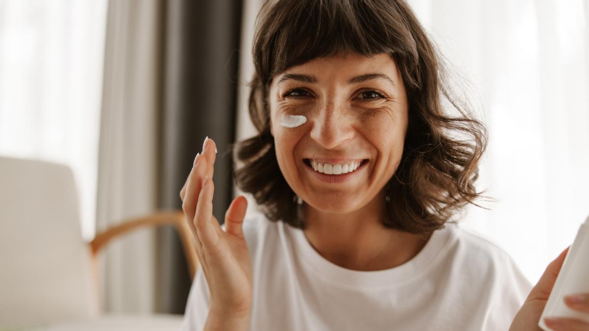 Chica se aplica crema en la cara para cuidar su piel.