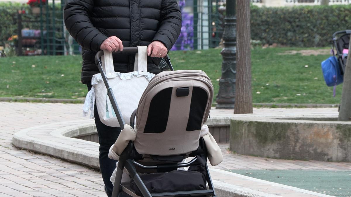 Un hombre empuja un carrito de bebé.