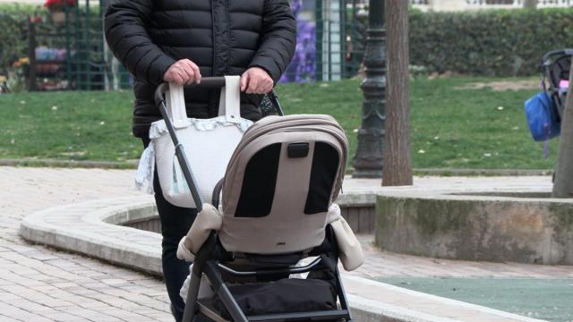 Un hombre empuja un carrito de bebé.
