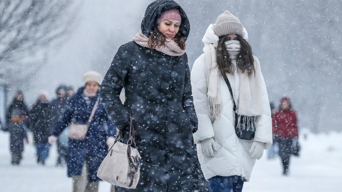 Dos jóvenes pasean bajo la nieve en Moscú.
