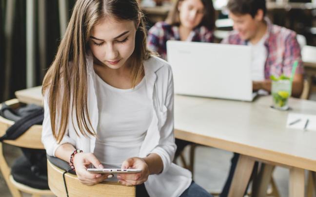 Una chica usa un dispositivo móvil durante una clase escolar.
