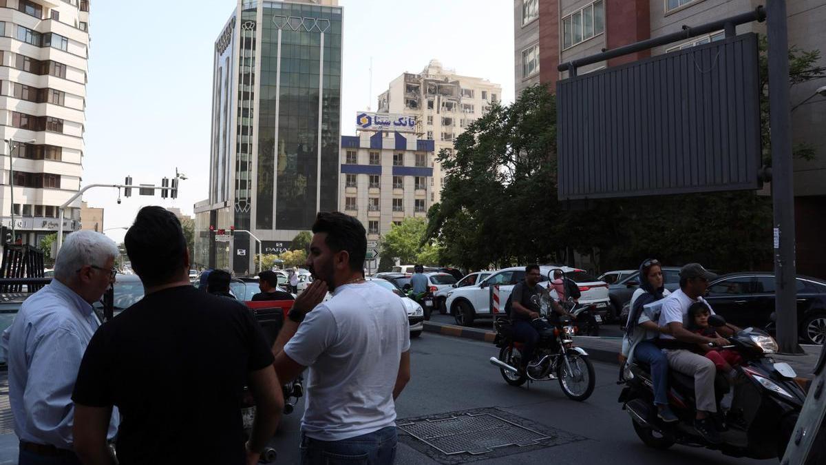 Varias personas observan los destrozos causados por un ataque israelí en un edificio de Teherán.