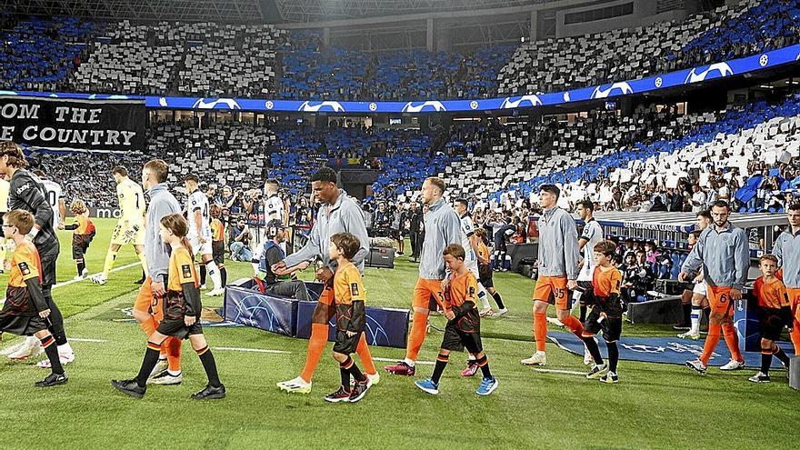 El Inter y la Real saltan al campo con el mosaico de la afición de fondo, en el partido inaugural de la Champions. / RUBEN PLAZA
