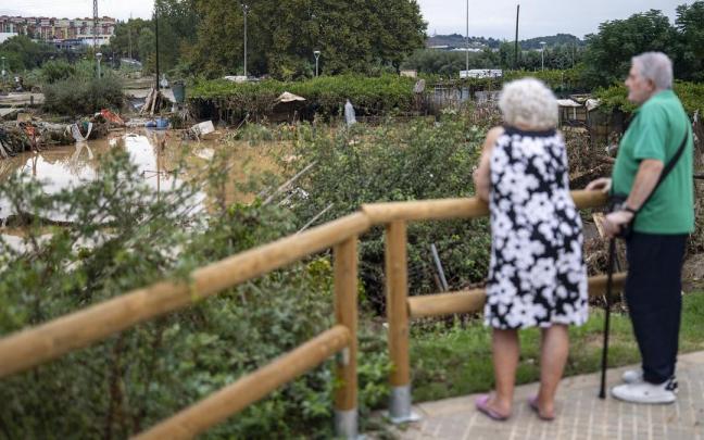 Dos personas observan el barro y el agua embolsada a causa de las lluvias torrenciales, a 4 de octubre de 2026, en Montornès del Vallès, Barcelona.