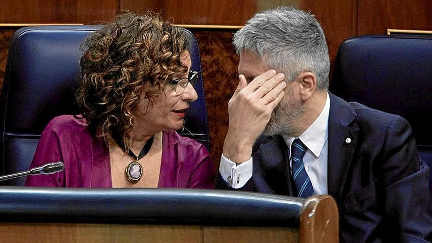 Grande-Marlaska se oculta el rostro mientras conversa con la ministra María Jesús Montero. | FOTO: E. P.